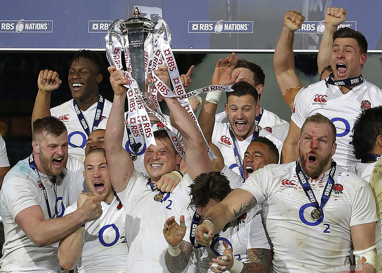  England's Dylan Hartley holds the trophy aloft as he celebrates with teammates after the Six Nations international rugby match between France and England at the Stade de France stadium in Saint-Denis, outside Paris, on March 19, 2016. England won th