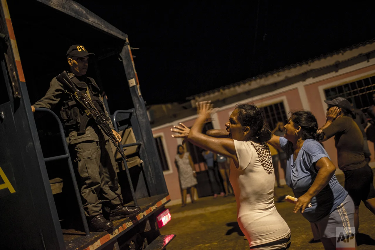 In this Nov. 10, 2016 photo, women argue with a National Guard, saying they've detained the wrong men while cracking down on pirates in Punta de Araya, Sucre state, Venezuela. After villagers protested they knew their suspects to be honest fishermen, the soldiers let the three men go. (AP Photo/Rodrigo Abd)