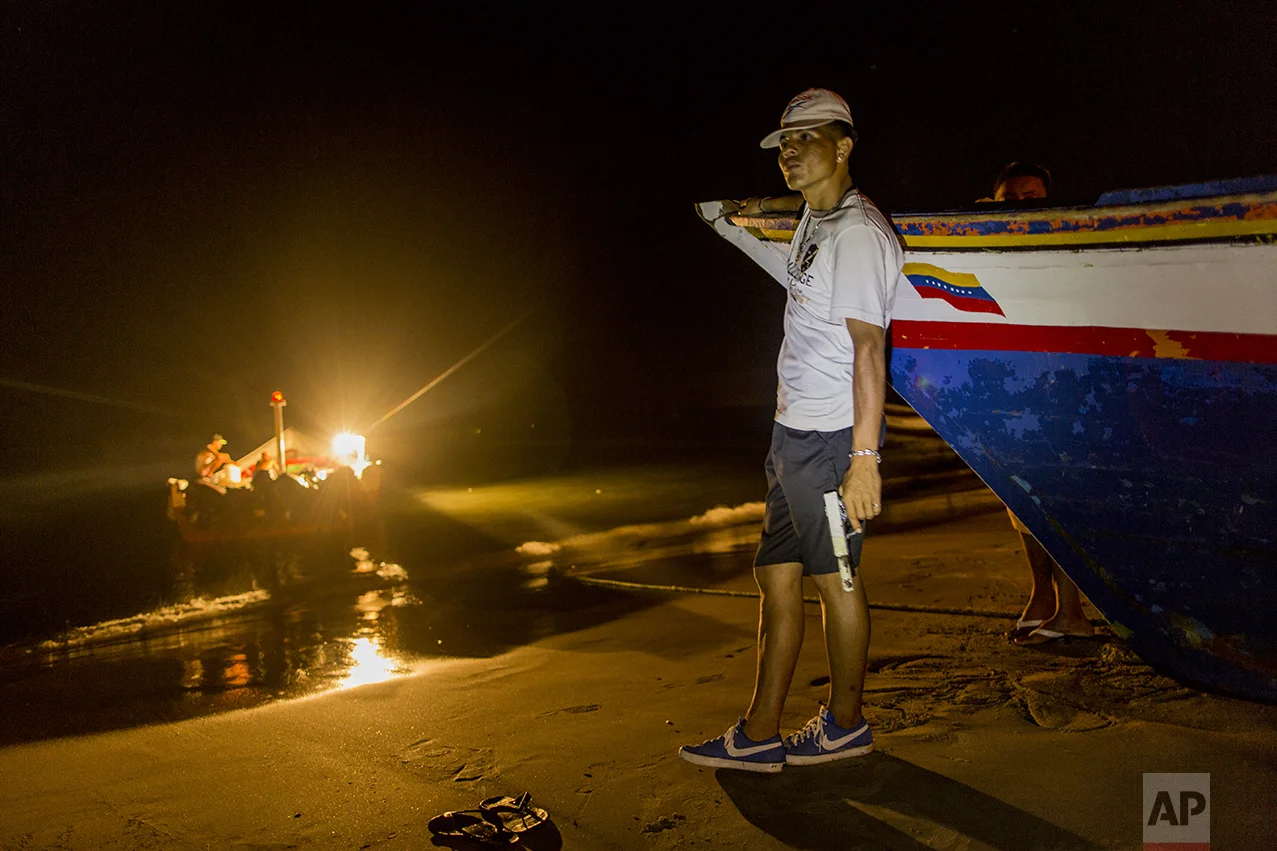 In this Nov. 2, 2016 photo, a member of the Marval fishing family who goes by the nickname "El Chukiti" holds a homemade gun as he guards against a possible pirate attack as fishermen unload their catch in Punta de Araya, Sucre state, Venezuela. The family's self-defense group calls themselves "Los Cainos." (AP Photo/Rodrigo Abd)