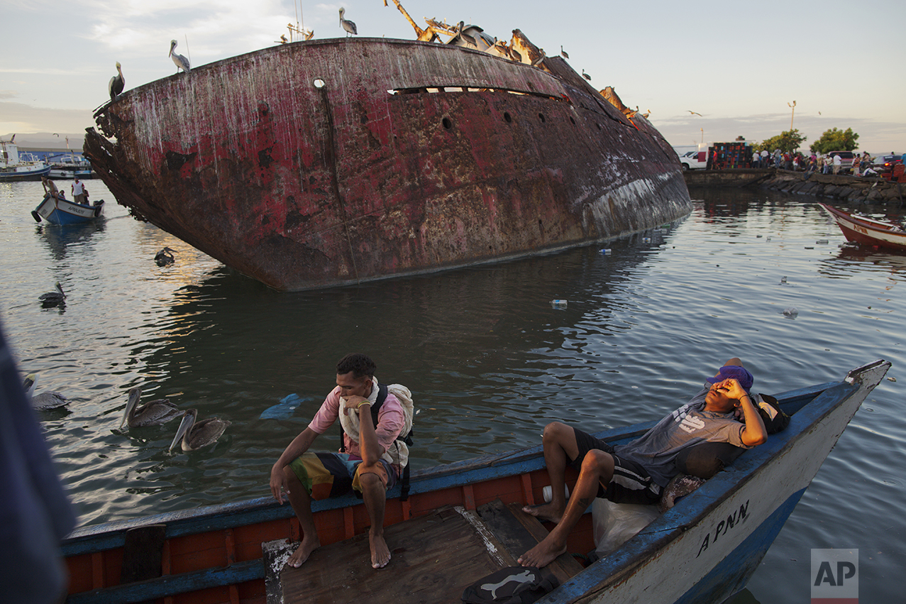 In this Nov. 30, 2016 photo, fishermen rest after selling their catch at the fish market in the port of Cumana, Sucre state, Venezuela. Here on the coast, the tuna catch is down to less than a third of the 120,000 tons Venezuela produced in 2004. (AP Photo/Rodrigo Abd)