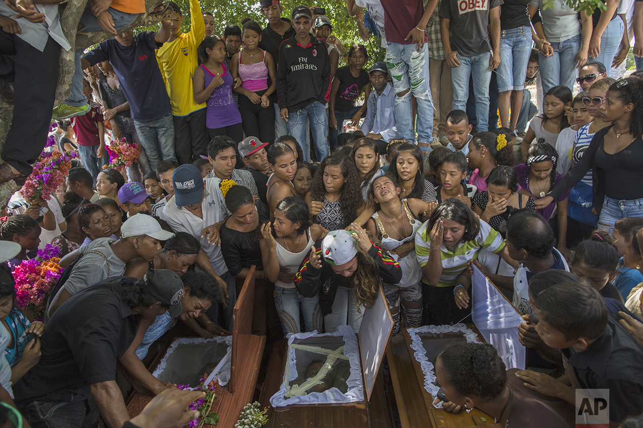 In this Nov. 13, 2016 photo, relatives of nine men from a fishing family, who were shot in the head while on their knees, mourn them at the cemetery in Cariaco, Sucre state, Venezuela. Five law enforcement officers were charged with storming the village and killing these men, who were widely thought to have belonged to a gang. (AP Photo/Rodrigo Abd)
