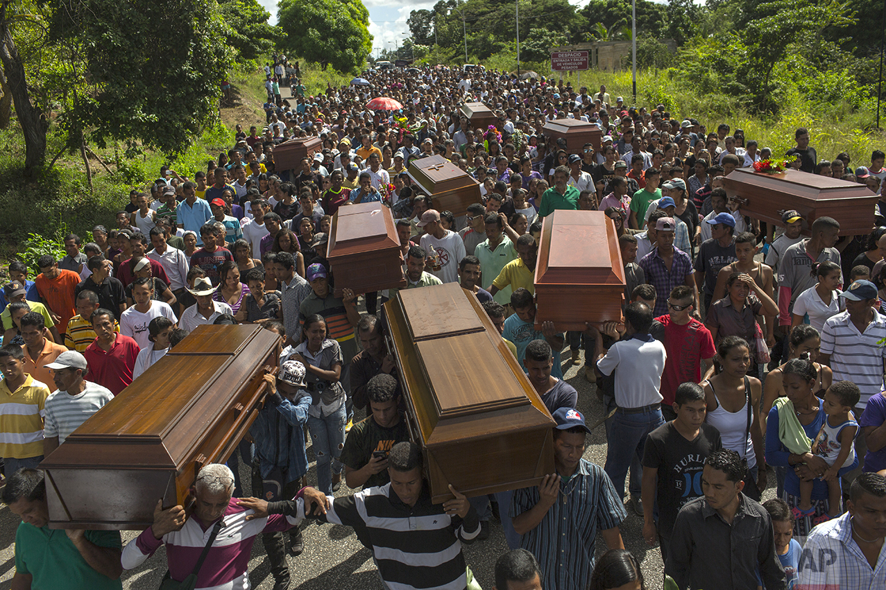 In this Nov. 13, 2016 photo, villagers carry the remains of nine slain men from a fishing family to the cemetery in Cariaco, Sucre state, Venezuela. Five law enforcement officers were charged with storming the village and killing these men, who were widely thought to have belonged to a gang. (AP Photo/Rodrigo Abd)