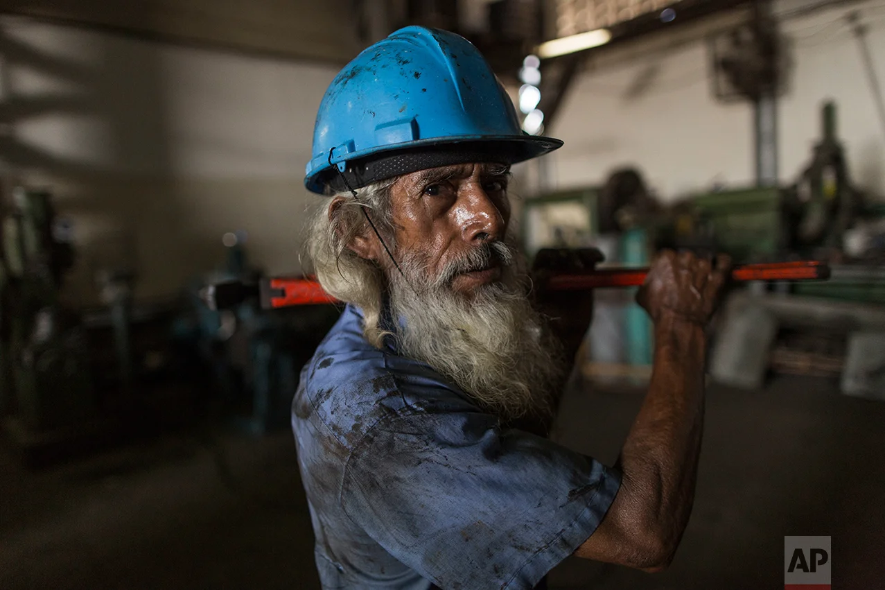 In this Oct. 29, 2016 photo, tuna ship mechanic Jose Noriega, 66, stops for a portrait as he works in the state run fishing company Pescalba, in Cumana, Sucre state, Venezuela. The government nationalized Pescalba in 2010. (AP Photo/Rodrigo Abd)