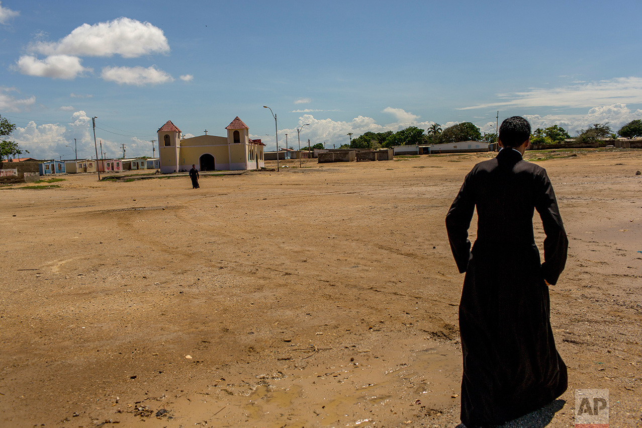 In this Nov. 6, 2016 photo, a priest walks to the chapel in Punta de Araya, Sucre state, Venezuela. The local church is trying to mediate between rival gangs in the area. (AP Photo/Rodrigo Abd)