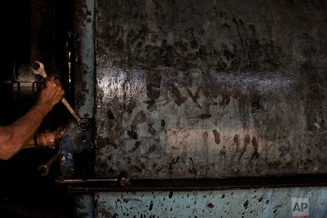 In this Nov. 3, 2016 photo, a worker repairs machinery to get it ready for the next sugar cane harvest at a sugar mill in Cumanacoa, Sucre state, Venezuela. The sugar and fish processing plants work at half capacity on good days. (AP Photo/Rodrigo Abd)