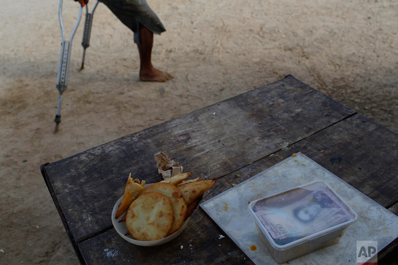 This Nov. 2, 2016 photo shows cash earned by a street vendor selling "empanadas" on a table in Punta de Araya, Sucre state, Venezuela. In the nation's capital, people bang pots at nightfall to protest the country's economic ruin, doctors shut down hospitals in protest, and students march on government buildings to demand relief. But the collapse has been far more savage in the rest of the country, and far less visible. (AP Photo/Rodrigo Abd)