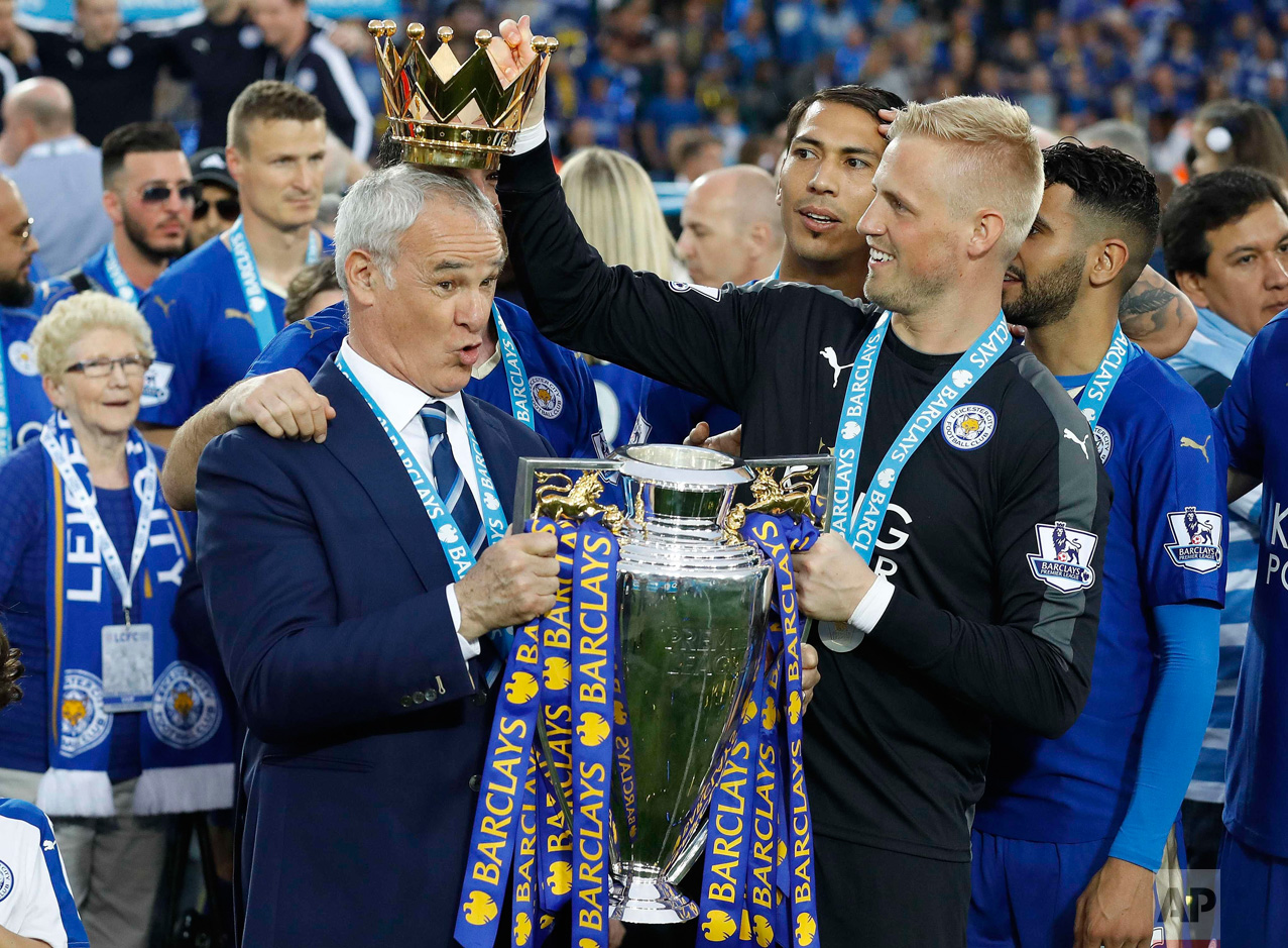  In this Saturday, May 7, 2016 photo, Leicester City team manager Claudio Ranieri has the crown of the trophy placed on his head by Leicester goalkeeper Kasper Schmeichel as they celebrate becoming the English Premier League soccer champions at King 