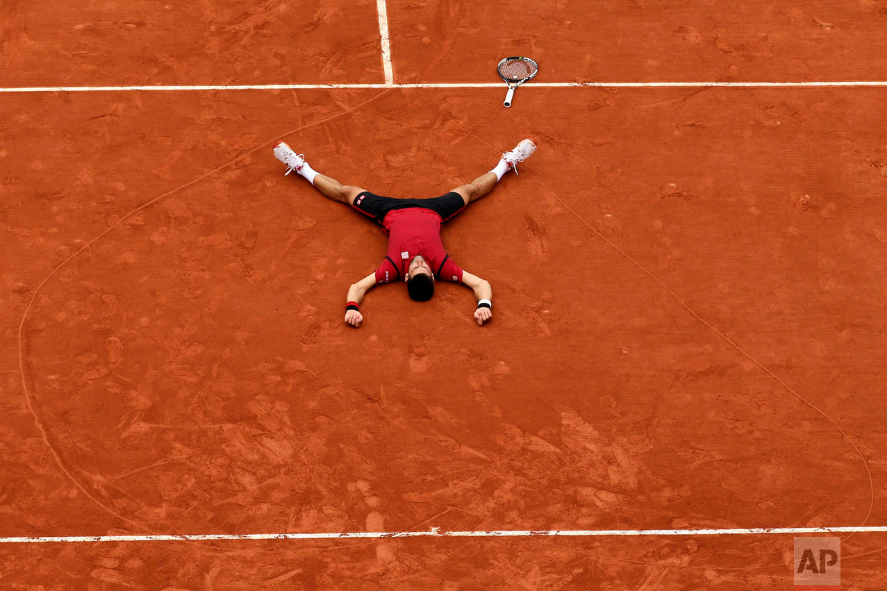  In this Sunday, June 5, 2016 photo, Serbia's Novak Djokovic lays on the clay in a heart in drew after defeating Britain's Andy Murray during their final match of the French Open tennis tournament at the Roland Garros stadium in Paris. Djokovic won 3