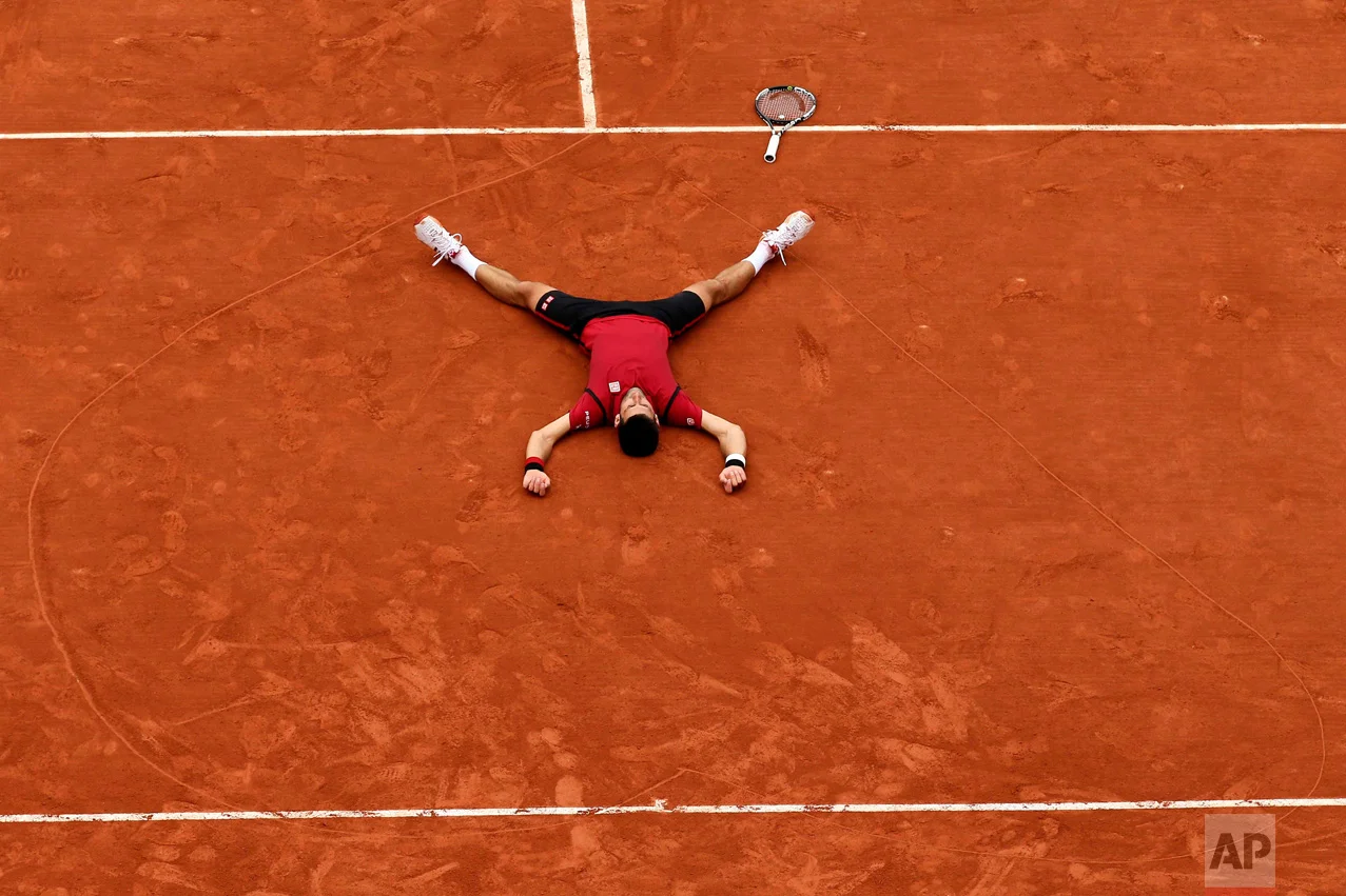 In this Sunday, June 5, 2016 photo, Serbia's Novak Djokovic lays on the clay in a heart in drew after defeating Britain's Andy Murray during their final match of the French Open tennis tournament at the Roland Garros stadium in Paris. Djokovic won 3-6, 6-1, 6-2, 6-4. (AP Photo/David Vincent)