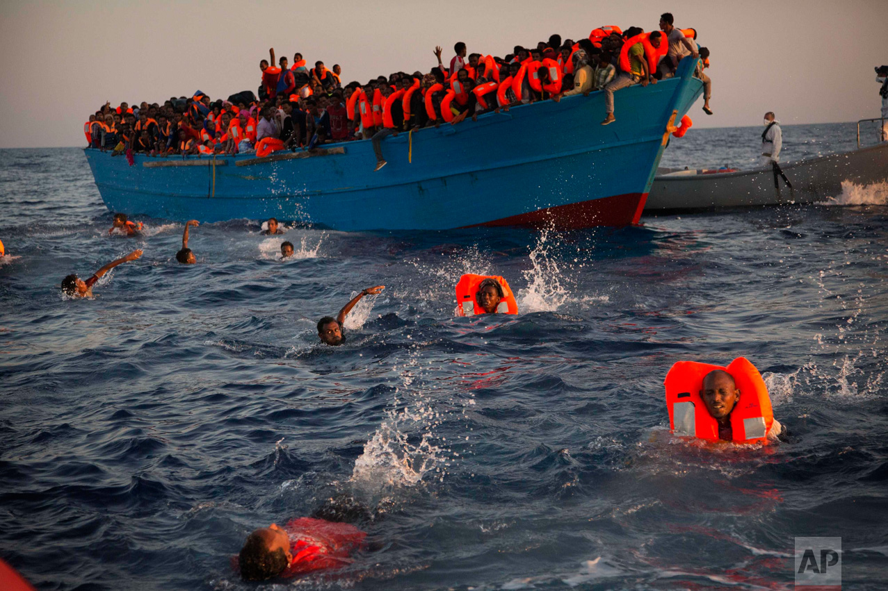  In this Monday, Aug. 29, 2016 photo, migrants, most of them from Eritrea, jump into the water from a crowded wooden boat as they are helped by members of an NGO during a rescue operation at the Mediterranean Sea, about 13 miles north of Sabratha, Li