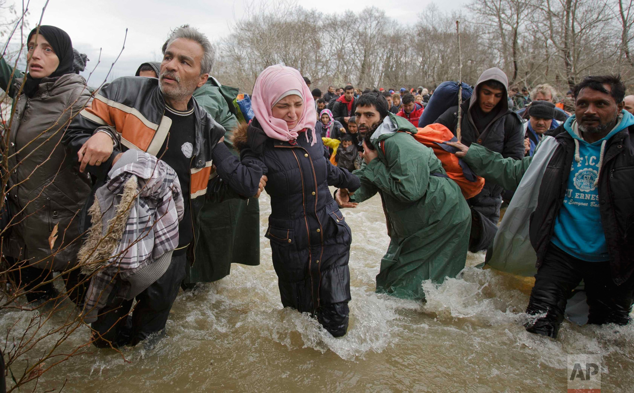  In this March 14, 2016 photo, a woman cries as she crosses the river along with other migrants, north of Idomeni, Greece, attempting to reach Macedonia on a route that would bypass the border fence. (AP Photo/Vadim Ghirda) 