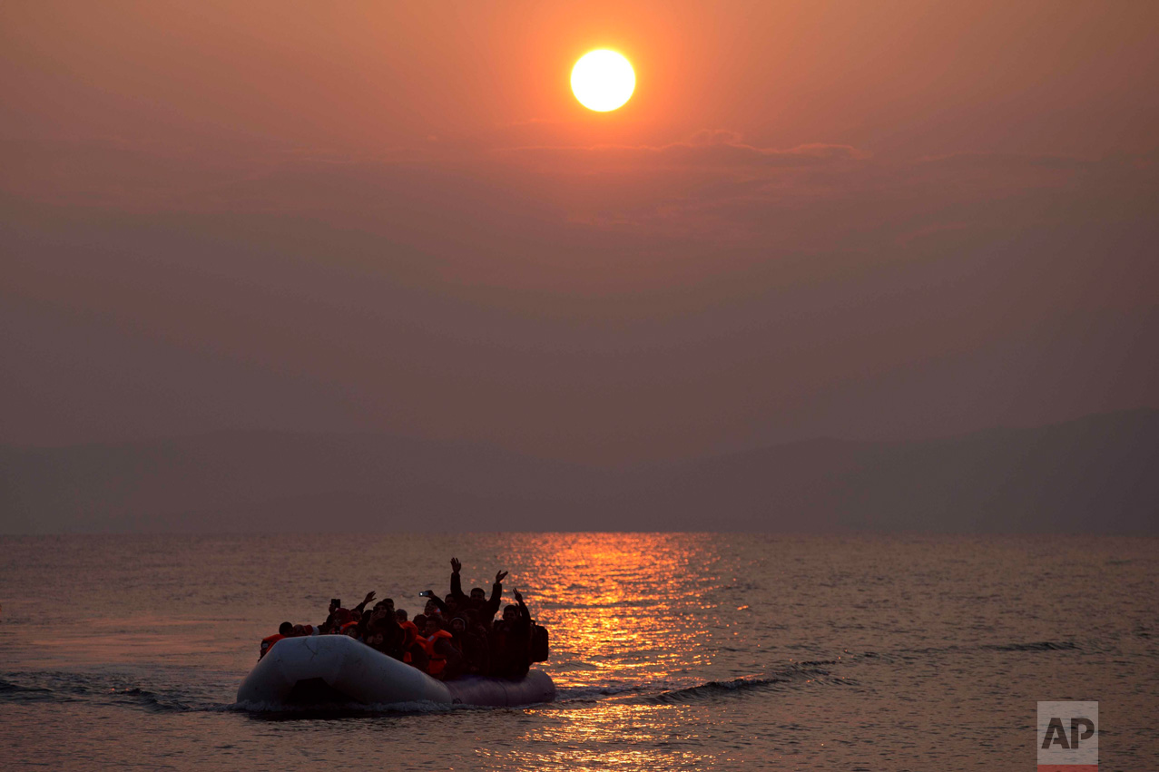  In this March 20, 2016 photo, the sun rises as migrants and refugees on a dingy arrive at the shore of the northeastern Greek island of Lesbos, after crossing the Aegean sea from Turkey (AP Photo/Petros Giannakouris) 