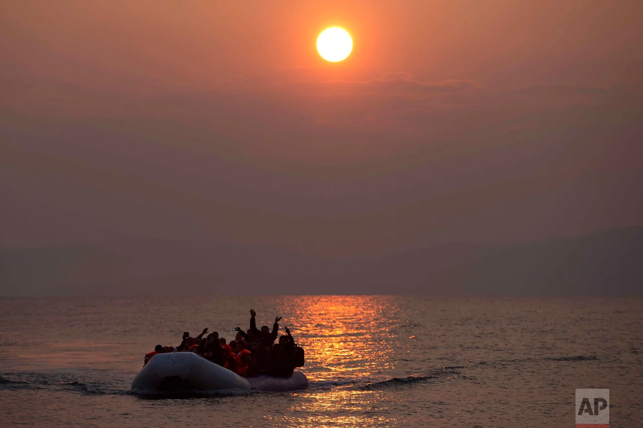 In this March 20, 2016 photo, the sun rises as migrants and refugees on a dingy arrive at the shore of the northeastern Greek island of Lesbos, after crossing the Aegean sea from Turkey (AP Photo/Petros Giannakouris)