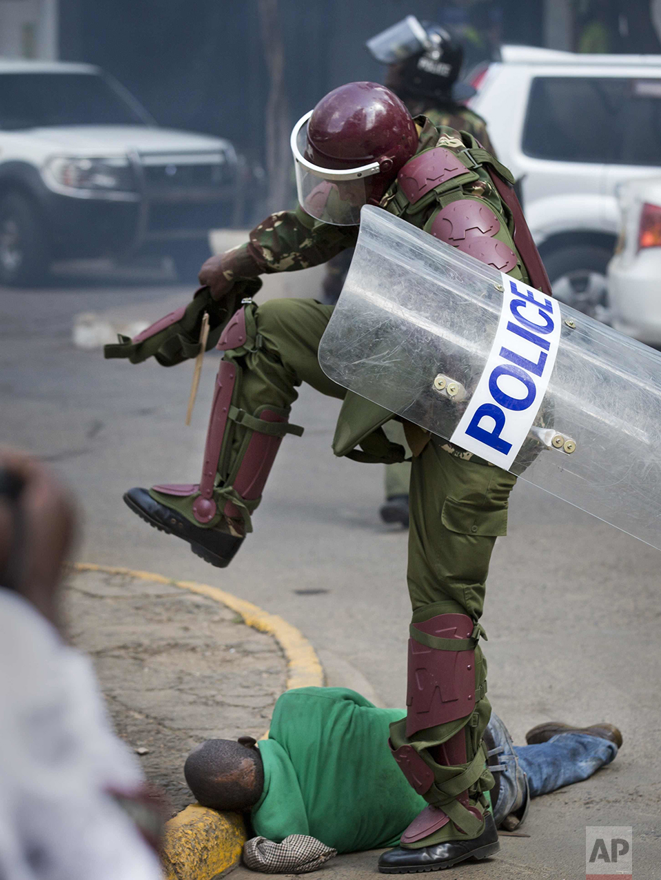  In this Monday, May 16, 2016 photo, a Kenyan riot policeman repeatedly kicks a protester as he lies in the street after tripping over while trying to flee from them, during a protest in downtown Nairobi, Kenya. Kenyan police have tear-gassed and bea