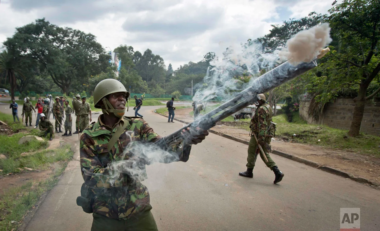 In this Monday, May 9, 2016 photo, a riot policeman fires tear gas towards opposition supporters during a protest in downtown Nairobi, Kenya. Kenyan police have tear-gassed opposition supporters after some pelted police with rocks during a protest demanding the disbandment of the electoral authority over alleged bias and corruption. (AP Photo/Ben Curtis)