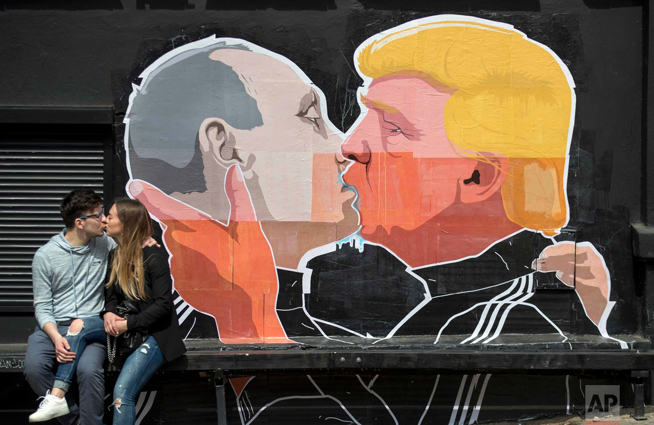  In this Saturday, May 14, 2016 photo, a couple kisses in front of graffiti depicting Russian President Vladimir Putin, left, and Republican presidential candidate Donald Trump, on the walls of a bar in the old town in Vilnius, Lithuania. (AP Photo/M