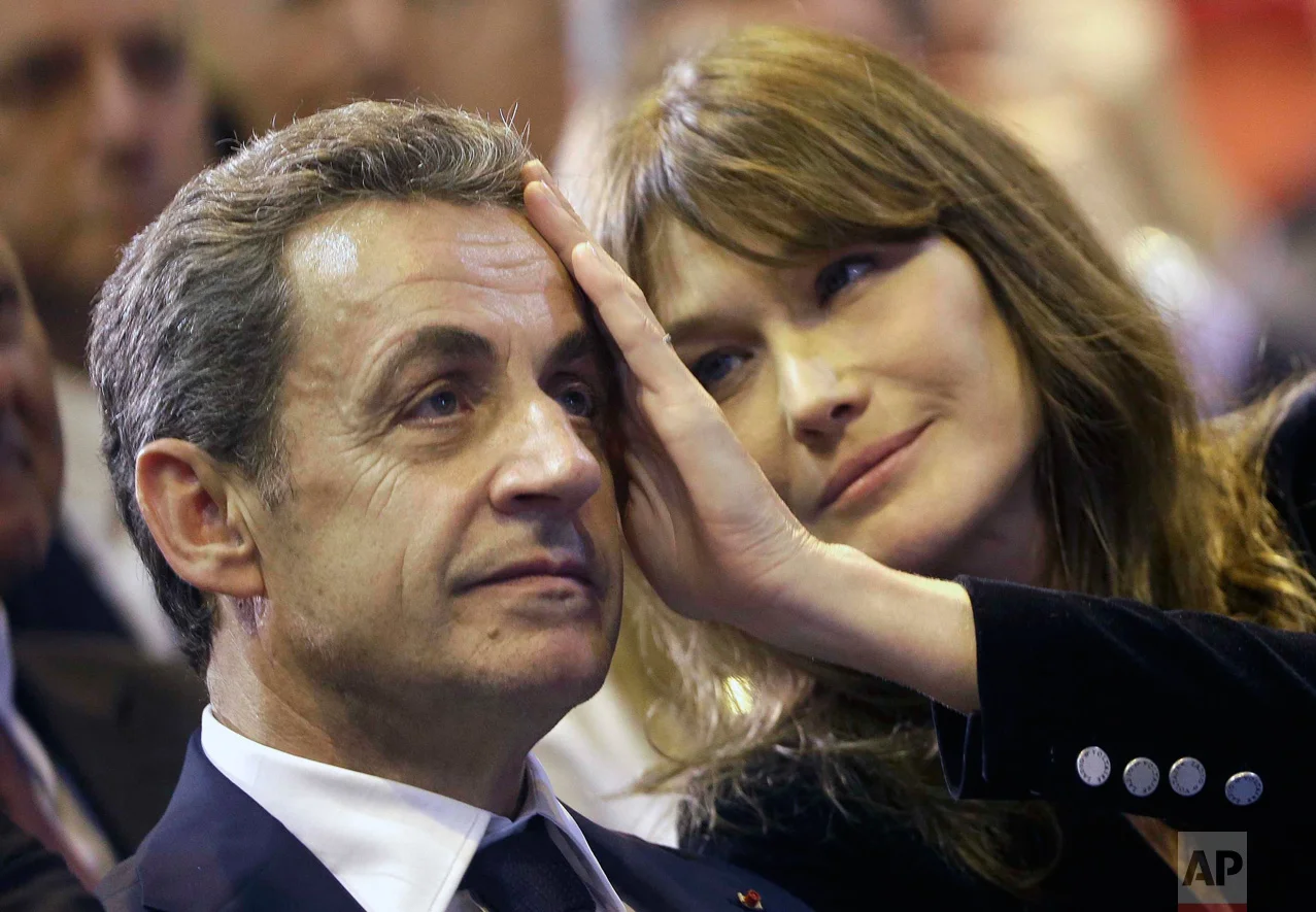 In this Thursday, Oct. 27, 2016 photo, Carla Sarkozy, right, caresses the brow of her husband, the former French President and candidate for France's conservative presidential primary, Nicolas Sarkozy, during a campaign meeting in Marseille, southern France. (AP Photo/Claude Paris)