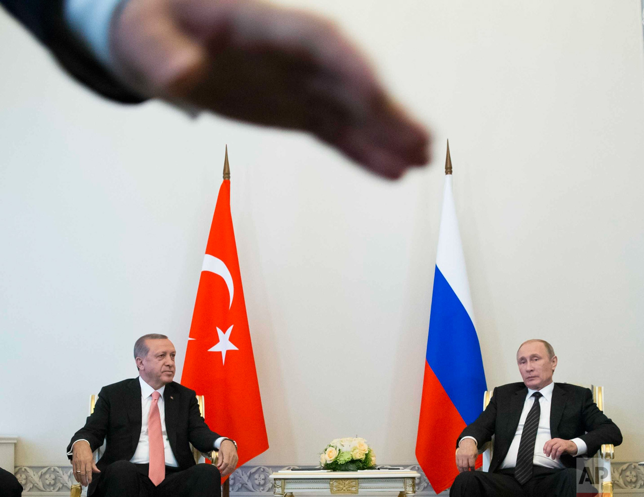  In this Tuesday, Aug. 9, 2016 photo, Russian President Vladimir Putin, right, and Turkish President Recep Tayyip Erdogan talk during their meeting, as a security member tries to stop photographers taking pictures, in the Konstantin palace outside St