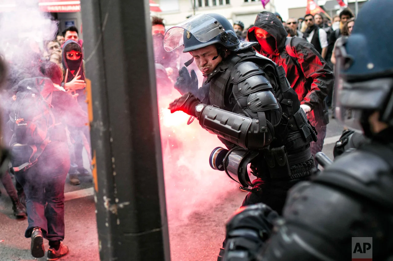 In this Thursday, April 28, 2016 photo, a policeman reacts during a clash with protestors during a protest against the proposed changes to France's working week and layoff practices, in Lyon, central France. French protesters are back on the streets over proposed reforms to the country's labor rules and strikers have forced cancellations and delays at two airports serving Paris. (AP Photo/Laurent Cipriani)