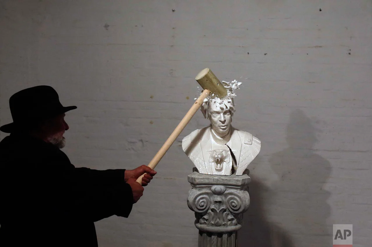 In this Friday, April 22, 2016 photo, Serbian artist Zivko Grozdanic smashes a statue of Prime Minister Aleksandar Vucic in the village of Veliko Srediste, Serbia. The provocative performance took place just one day before Sunday's early election when Vucic and his populist Progressive Party are expected to tighten an already firm grip on power. (AP Photo/Darko Vojinovic)