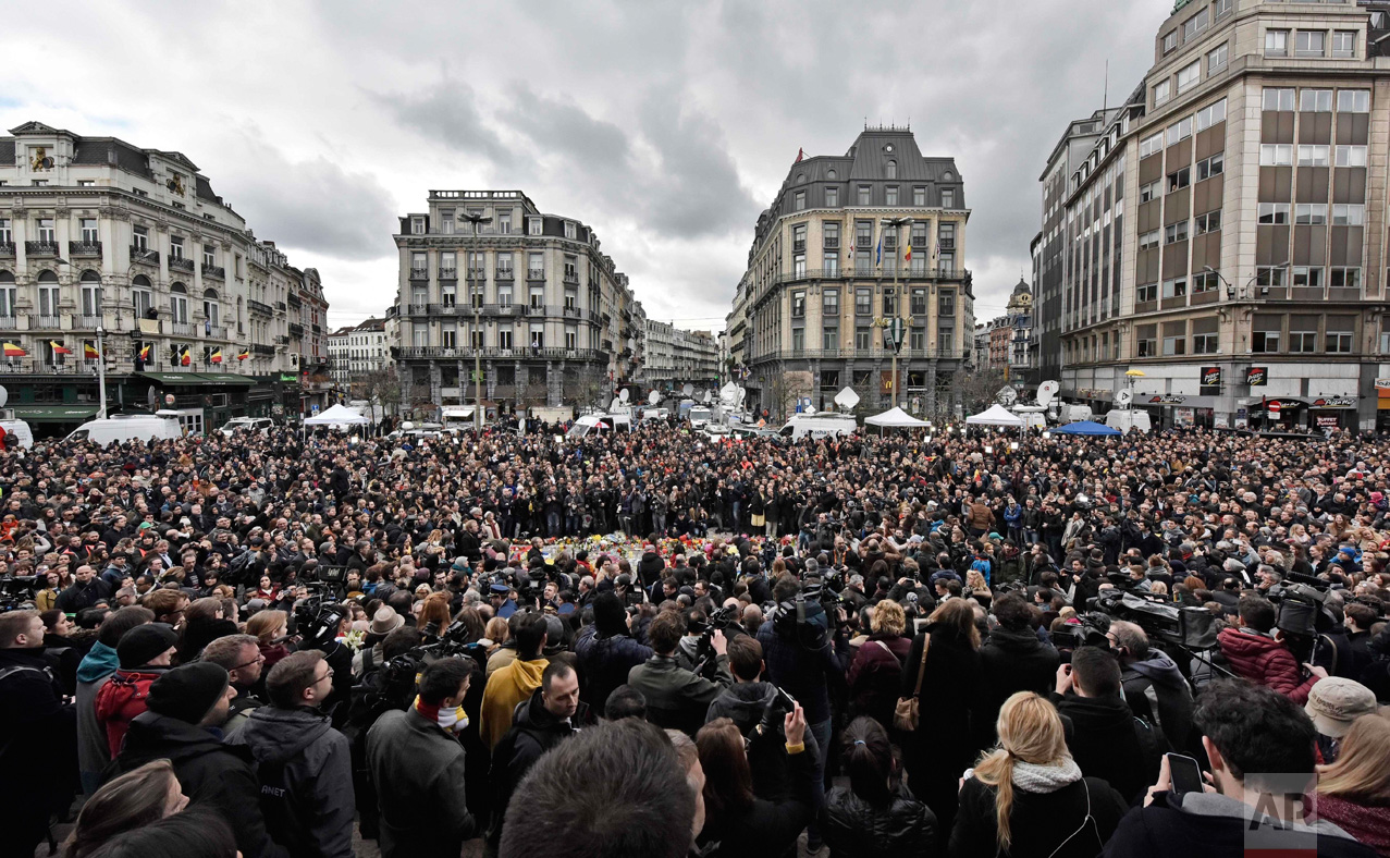  In this Wednesday, March 23, 2016 photo, people observe a minute of silence at the Place de la Bourse in the center of Brussels. Bombs exploded yesterday at the Brussels airport and one of the city's metro stations Tuesday, killing and wounding scor