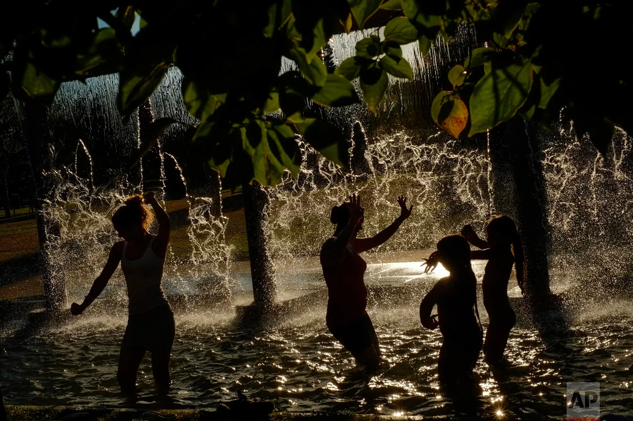 In this Wednesday, Aug. 24, 2016 photo, people cool off under a water fountain on a sunny day, in Pamplona northern Spain. The recent hot weather has prompted many people to cool off in the water fountains. (AP Photo/Alvaro Barrientos)