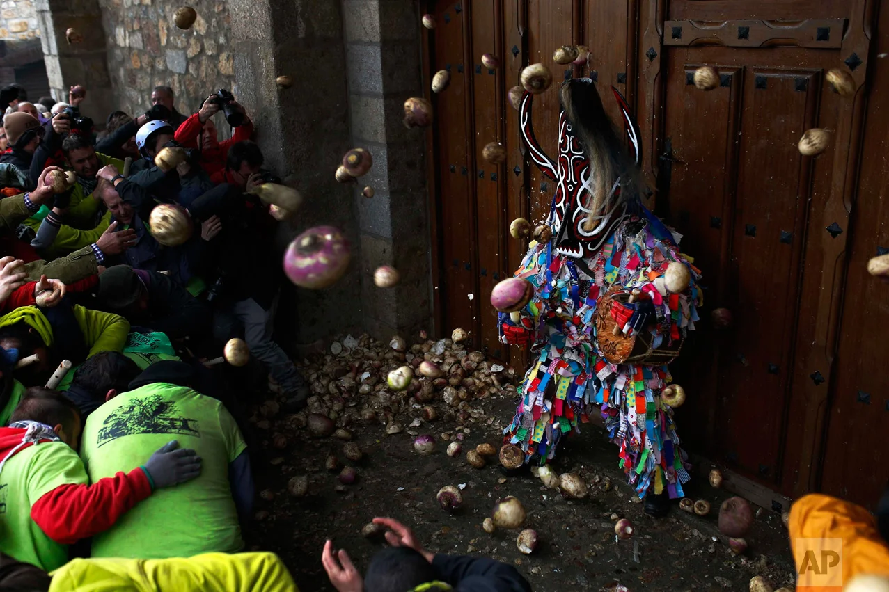 In this Wednesday, Jan. 20, 2016 photo, people throw turnips at the Jarramplas as he makes his way through the streets beating his drum during the Jarramplas festival in Piornal, Spain. (AP Photo/Francisco Seco)