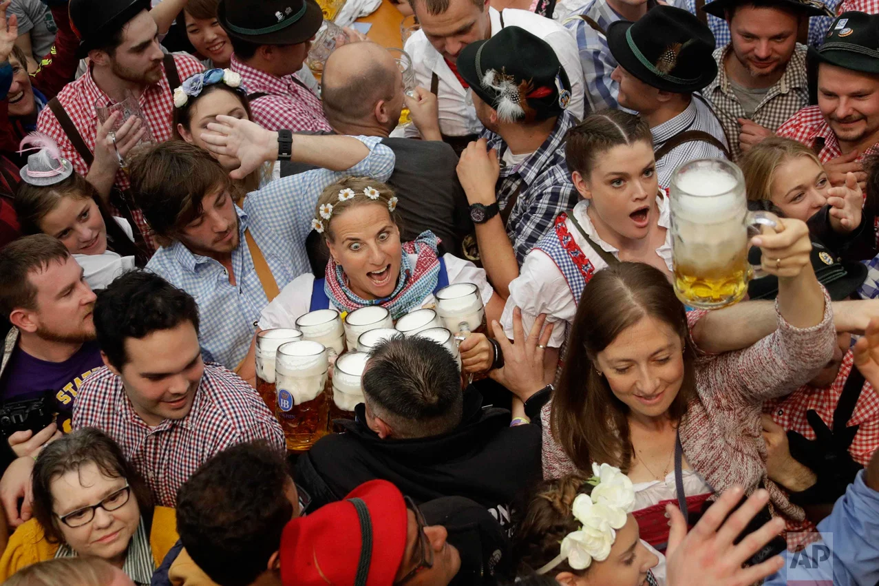 In this Saturday, Sept. 17, 2016 photo, a waitress is surrounded by visitors during the opening ceremony of the 183rd Oktoberfest beer festival in Munich, southern Germany. (AP Photo/Matthias Schrader)
