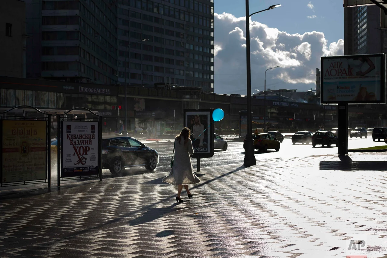 In this Thursday, Sept. 8, 2016 photo, a pedestrian holds a balloon after a rain in Moscow, Russia. (AP Photo/Alexander Zemlianichenko)