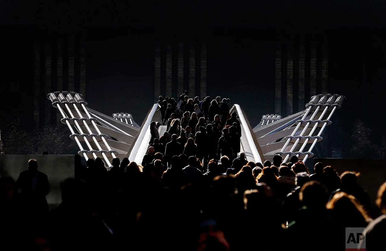 In this Tuesday, Feb. 16, 2016 photo, pedestrians stroll over the Millennium Bridge in London. Temperatures dropped below zero overnight and daytime showed a clear blue sky with bright sunshine. (AP Photo/Frank Augstein)