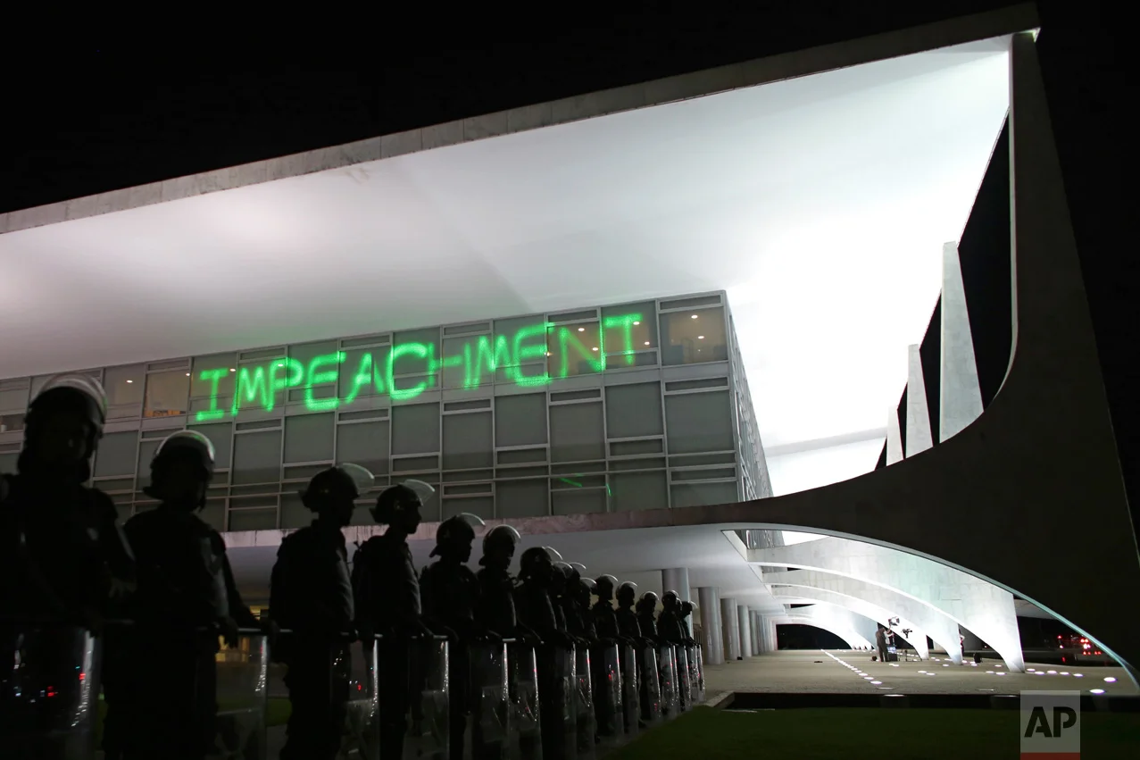 In this March 21, 2016 photo, soldiers stand guard outside the Planalto presidential palace where protesters have projected the word "Impeachment" on the building, as they call for the impeachment of Brazil's President Dilma Rousseff, in Brasilia, Brazil. About six months later senators voted to impeach and remove Rousseff, Brazil's first female president, from office. (AP Photo/Eraldo Peres)