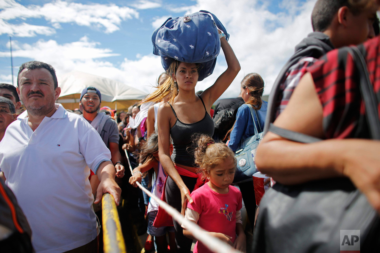  In this July 17, 2016 photo, a woman carrying a bundle on her head wait in line to cross the border into Colombia through the Simon Bolivar bridge in San Antonio del Tachira, Venezuela. In July tens of thousands of Venezuelans crossed the border int