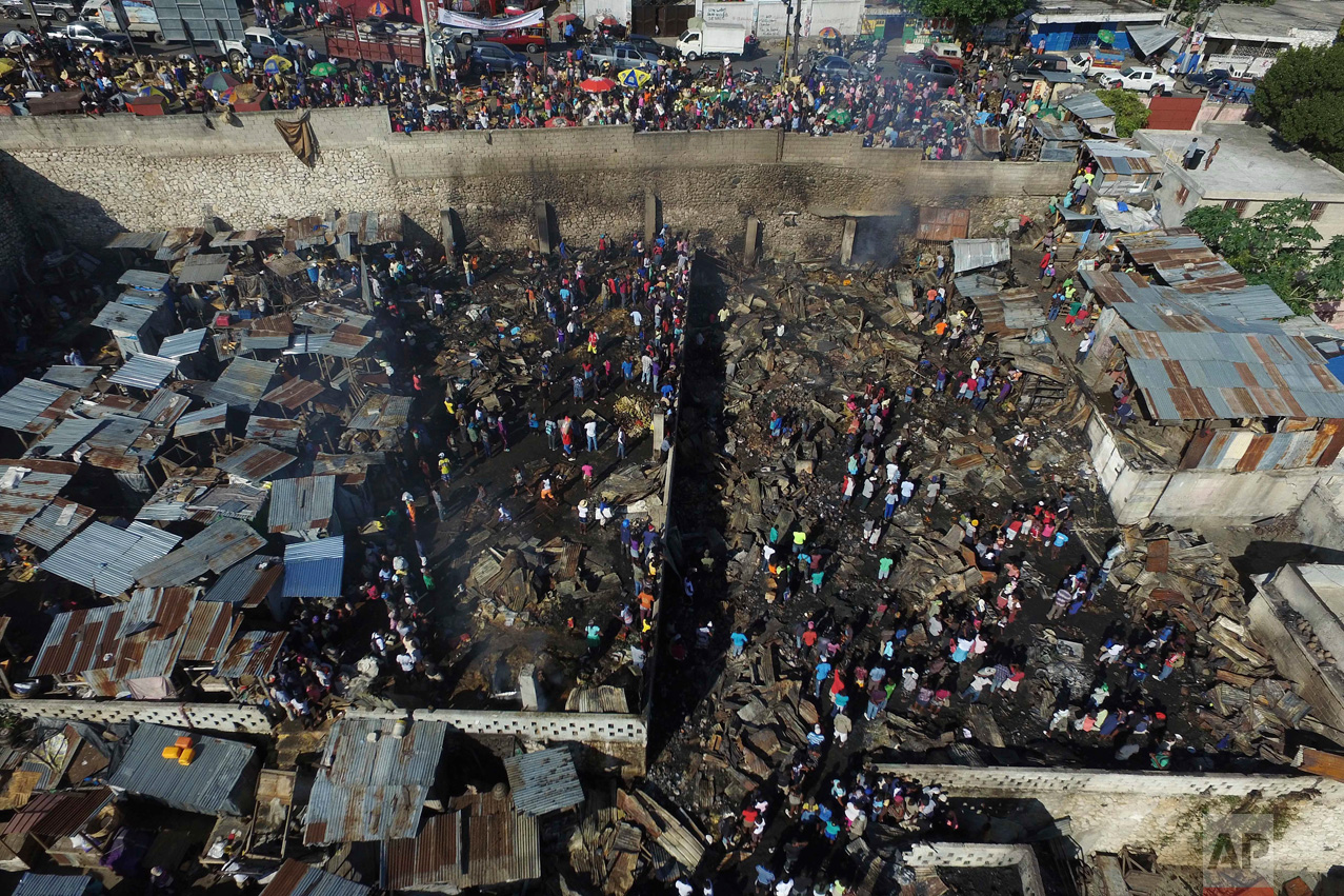  In this Nov. 21, 2016 photo, people walk through the charred remains of market shops gutted by an overnight fire in the Petion-Ville suburb of Port-au-Prince, Haiti. A major fire ripped through the central market in the hillside district above the c