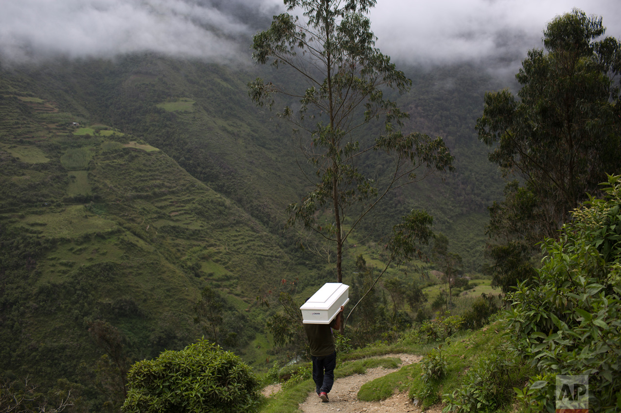  In this March 29, 2016 photo, a man shoulders a coffin with the remains of a loved one, who was slain more than two decades ago by Shining Path guerrillas, while walking to the cemetery for a mass burial service, in Huanta, Peru. The remains of 40 v