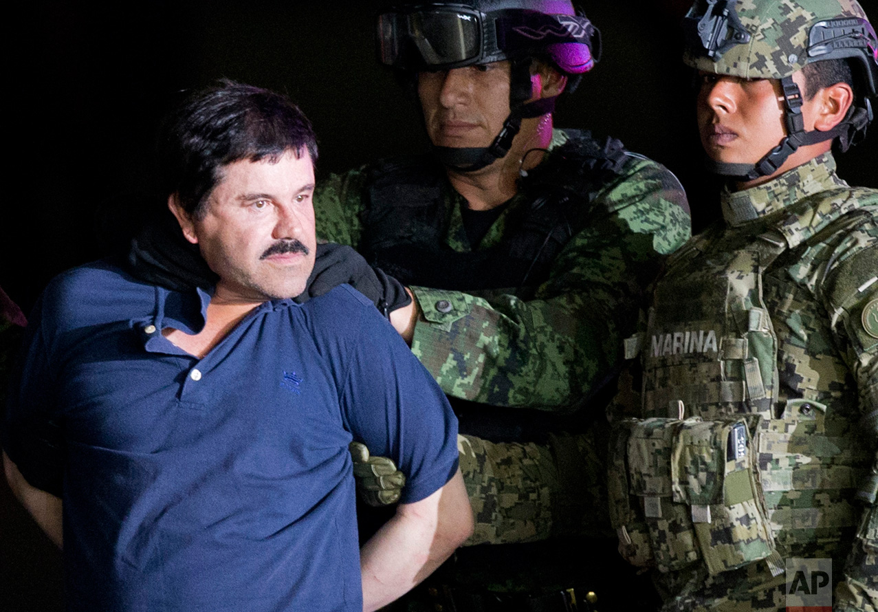  In this Jan. 8, 2016 photo, a handcuffed Joaquin "El Chapo" Guzman is made to face the press as he is escorted to a helicopter by Mexican soldiers and marines at a federal hangar in Mexico City. Mexican President Enrique Pena Nieto announced Guzman 