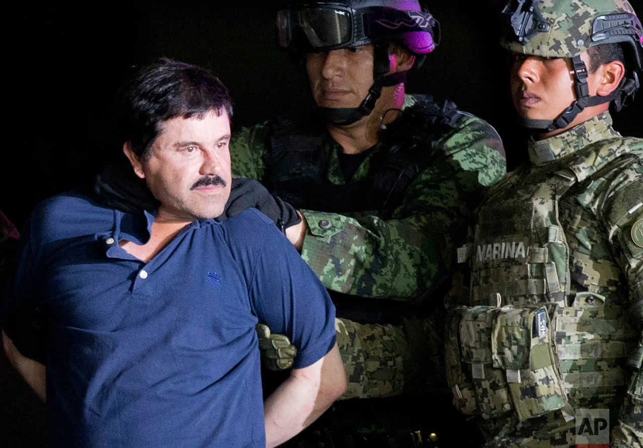 In this Jan. 8, 2016 photo, a handcuffed Joaquin "El Chapo" Guzman is made to face the press as he is escorted to a helicopter by Mexican soldiers and marines at a federal hangar in Mexico City. Mexican President Enrique Pena Nieto announced Guzman was recaptured six months after escaping from a maximum security prison. (AP Photo/Eduardo Verdugo)