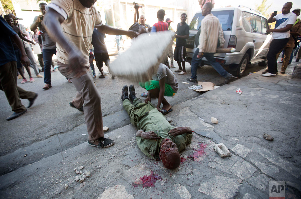  In this Feb. 5, 2016 photo, an anti-government protester drops a large cinderblock on the head of Neroce R. Ciceron, in Port-au-Prince, Haiti. A former captain of Haiti's disbanded army, Ciceron was beaten to death during a clash between members of 
