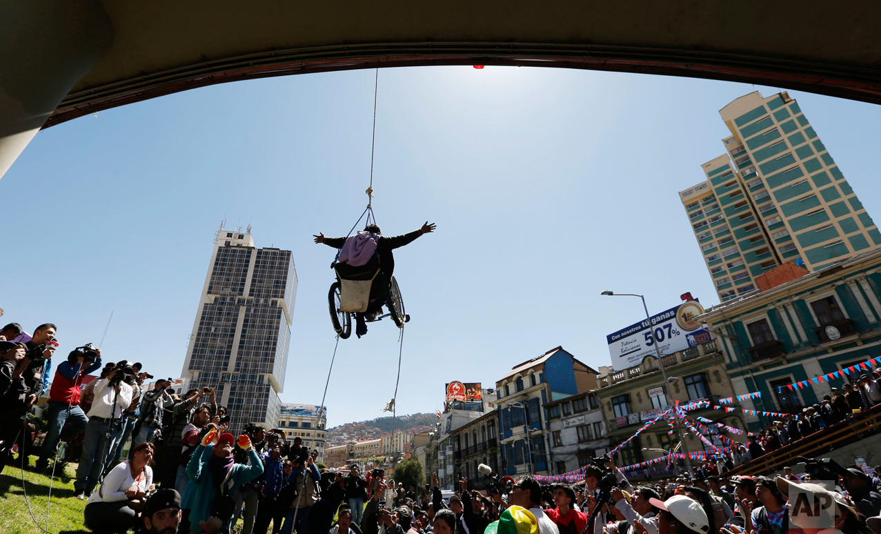  In this May 3, 2016 photo, a woman in a wheelchair hangs from a rope under a footbridge during a demonstration demanding better state benefits and equal rights for people with disabilities, in downtown La Paz, Bolivia. People protested for almost tw