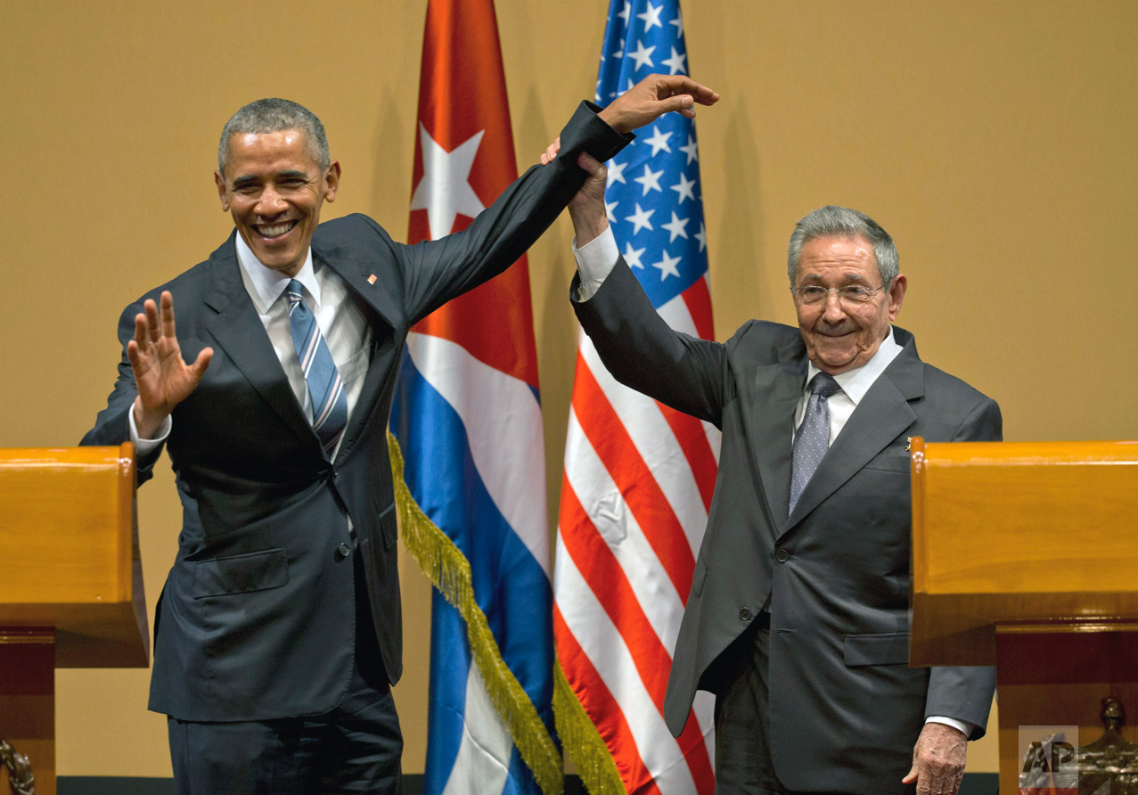  In this March 21, 2016 photo, Cuban President Raul Castro, right, lifts up the arm of President Barack Obama, at the conclusion of their joint news conference at the Palace of the Revolution, in Havana, Cuba. Obama was joined by wife Michelle Obama 