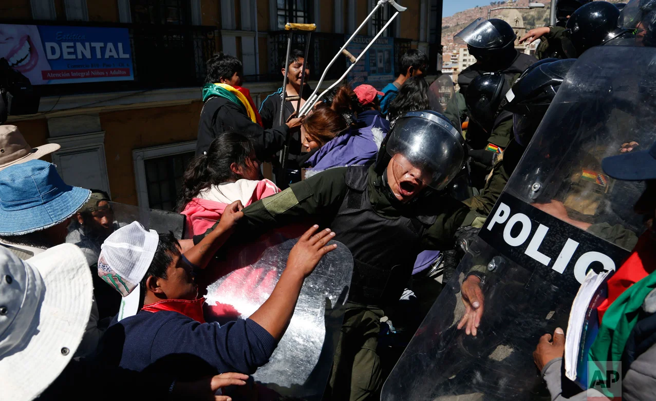 In this May 3, 2016 photo, protesters push against police who eventually failed to block them from reaching a footbridge where they planned a demonstration in downtown La Paz, Bolivia. The demonstration called attention to the group's demand for an increase in state benefits for those with disabilities. (AP Photo/Juan Karita)