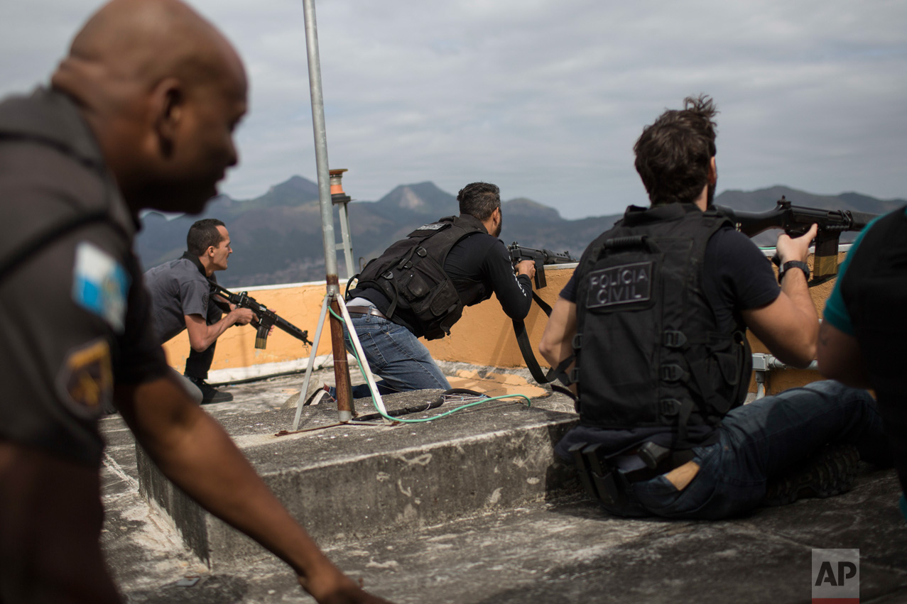  In this July 7, 2016 photo, police exchange gunfire with drug traffickers at the "pacified" Alemao slum complex in Rio de Janeiro, Brazil. Half a dozen officers had entrenched themselves behind a cable car station while they shot it out with suspect