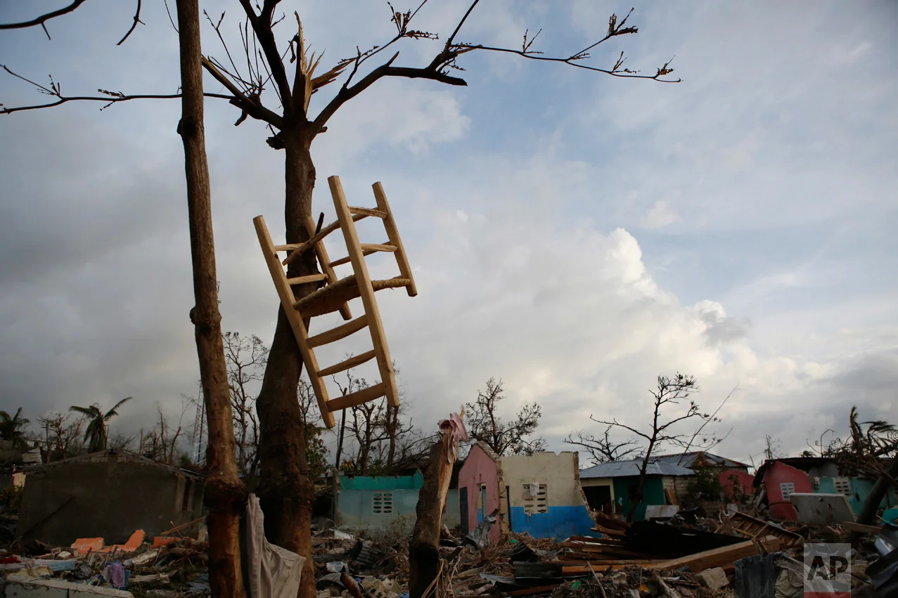 In this Oct. 9, 2016 photo, a salvaged chair hangs in a tree amidst nearby homes destroyed by Hurricane Matthew, in a seaside fishing neighborhood of Port Salut, Haiti. Nearly a week after the storm smashed into southwestern Haiti, some communities along the southern coast had yet to receive any assistance. Residents who lost their homes and virtually all of their belongings struggled to find shelter and potable water. (AP Photo/Rebecca Blackwell)
