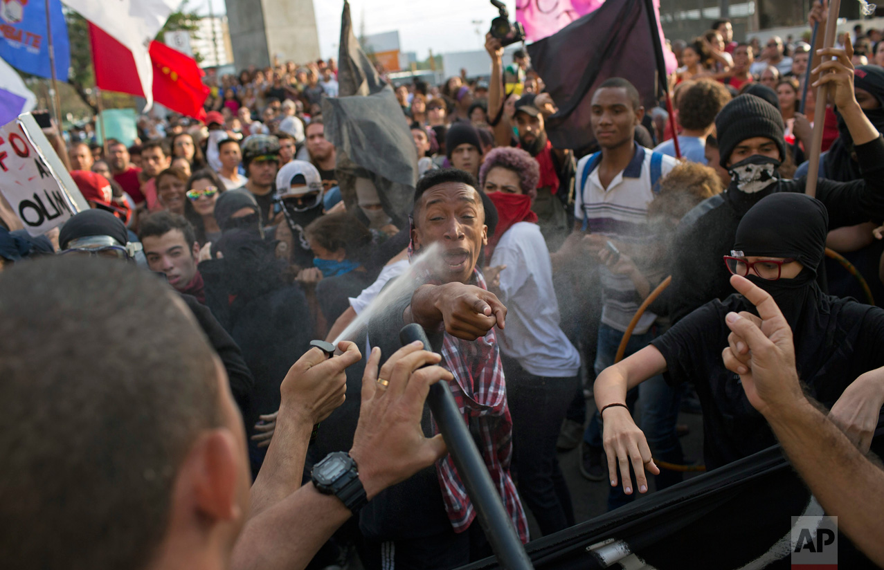  In this Aug. 2, 2016 photo, a police officer pepper sprays demonstrators as a scuffle breaks out during a protest against the money spent on Rio's 2016 Summer Olympics on the route of the Olympic torch, in Niteroi, Brazil. (AP Photo/Leo Correa) 