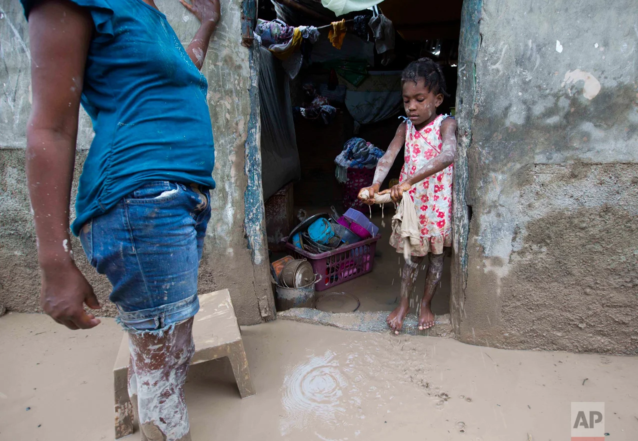 In this Oct. 6, 2016 photo, a girl helps her mother to remove mud after Hurricane Matthew flooded their home in Les Cayes, Haiti. Haitian and international agricultural officials said it could be a decade or more before the southwestern peninsula recovers economically from Hurricane Matthew, which struck hard at the rugged region of more than 1 million people that is almost completely dependent on farming and fishing. (AP Photo/Dieu Nalio Chery)