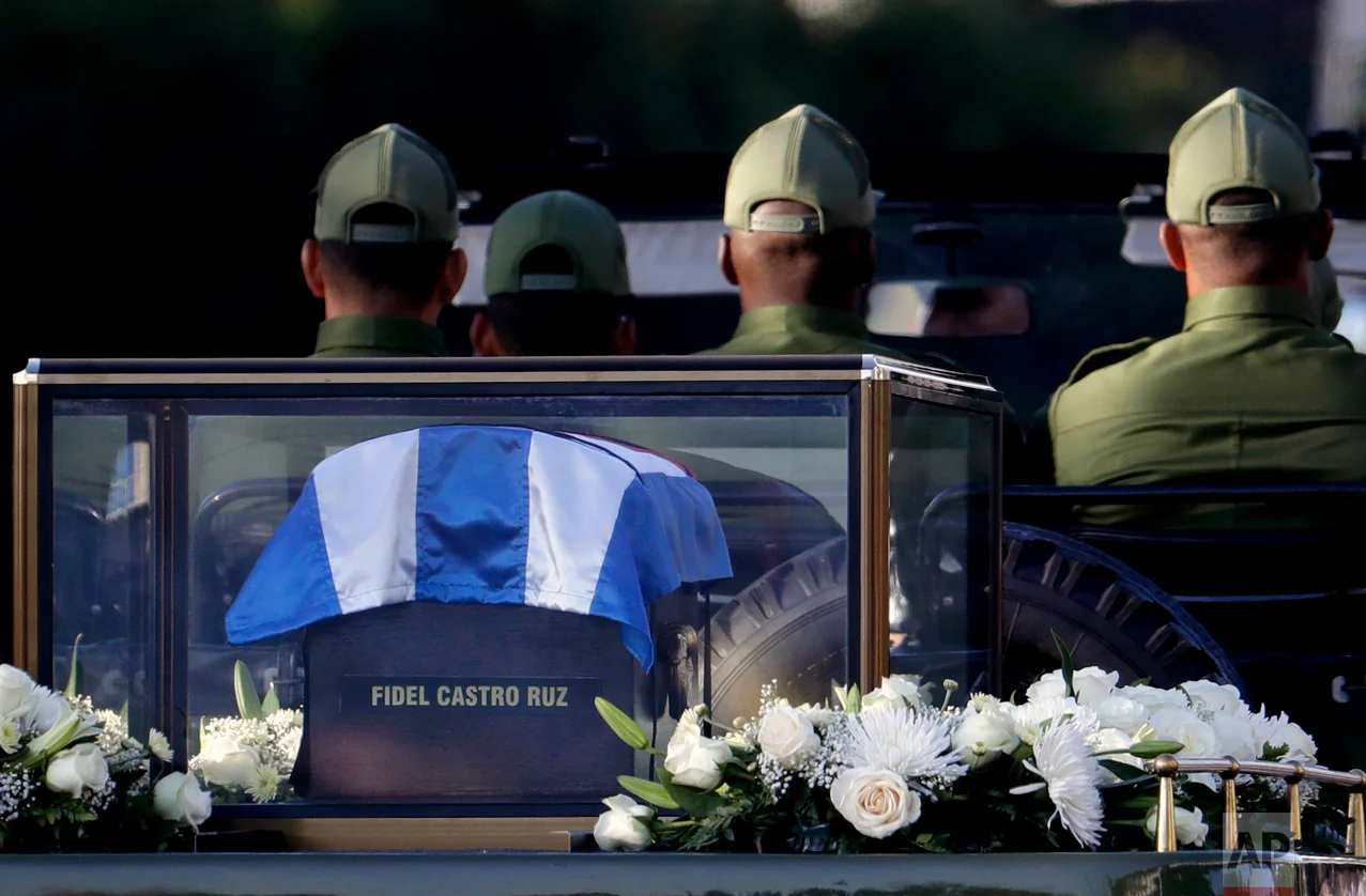 This Nov. 30, 2016 photo shows a flag-draped cedar coffin containing the remains of the late Cuban leader Fidel Castro driven through the streets of Havana, Cuba. Castro's ashes made a four-day journey across Cuba from Havana to their final resting place in the eastern city of Santiago, to retrace in reverse his triumphant march into Havana nearly six decades ago. (AP Photo/Natacha Pisarenko)
