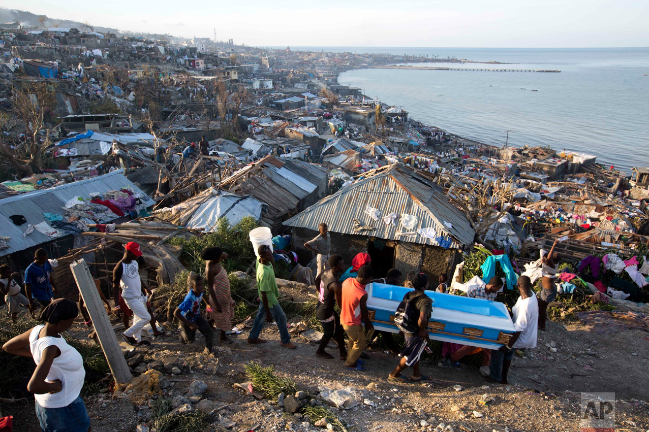  In this Oct. 7, 2016 photo, residents carry a coffin containing the remains of a pregnant woman, a victim of Hurricane Matthew, in Jeremie, Haiti. People across southwest Haiti dug through the wreckage of their homes, salvaging what they could of th