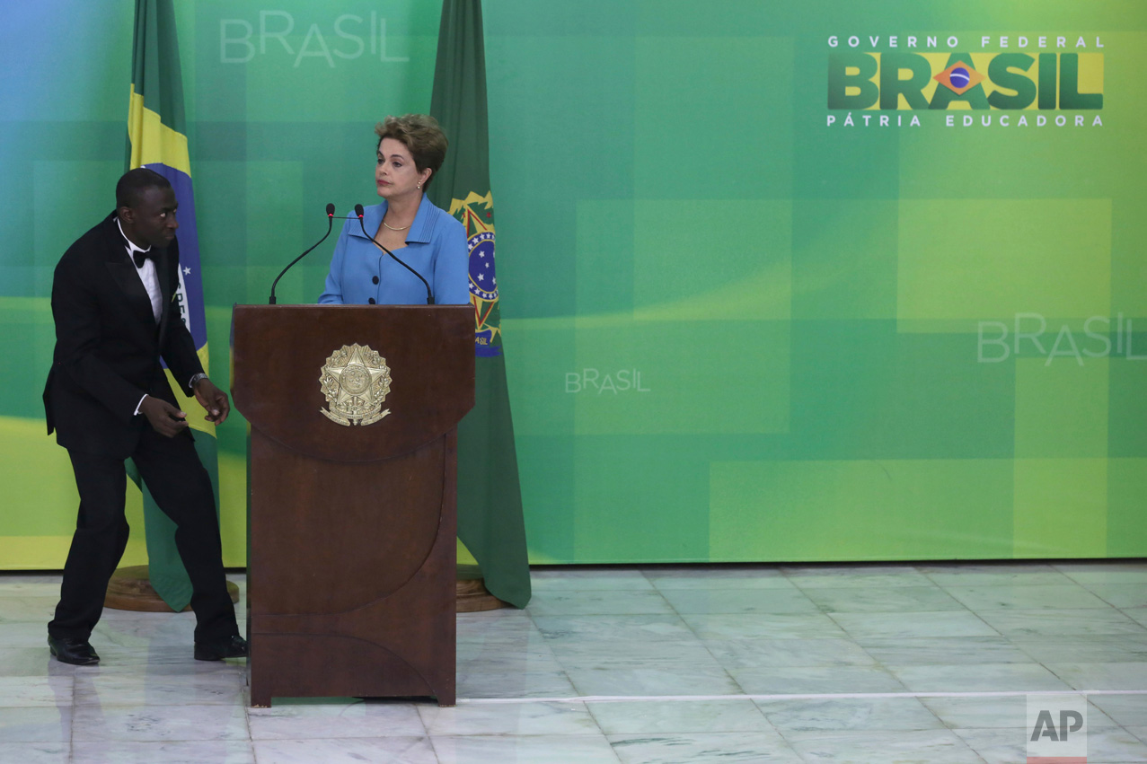  In this April 18, 2016 photo, a waiter walks in to serve water to Brazil's President Dilma Rousseff during a press conference where she spoke about her impeachment process, at Planalto Presidential Palace, in Brasilia. Rousseff, Brazil's first femal