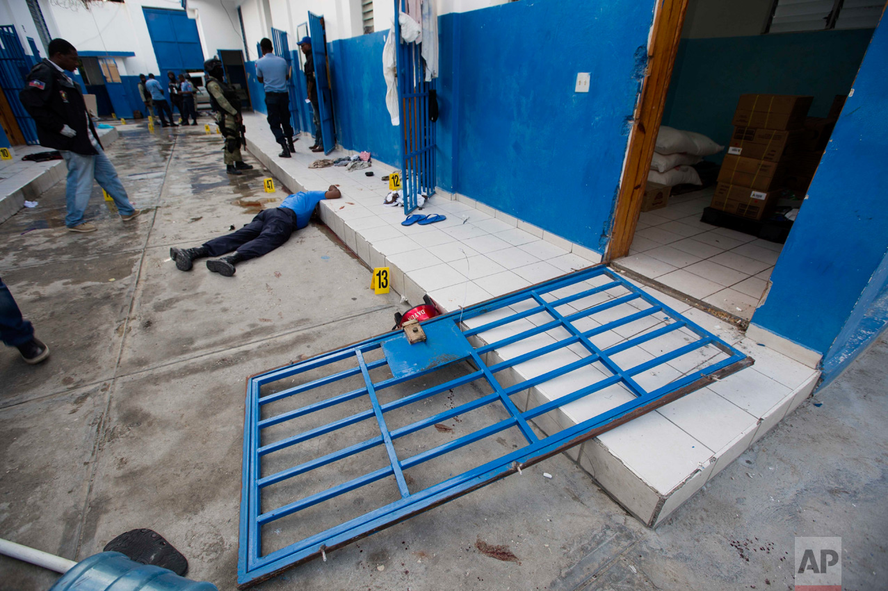  In this Oct. 22, 2016 photo, a guard lies dead inside the Civil Prison after a jail break in the coastal town of Arcahaiea, Haiti. Over 100 inmates escaped after they overpowered guards who were escorting them to a bathing area. Police officers sear