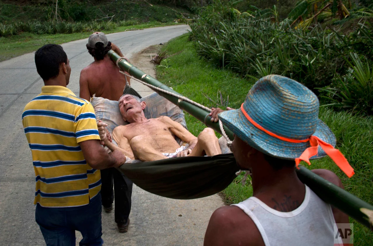 In this Oct. 6, 2016 photo, an elderly man, who was in a hospital before Hurricane Matthew hit, is carried home on a hammock in Baracoa, Cuba. He was carried back on foot because the roads were impassible due to damage caused by the storm, blocking all motor vehicle traffic to the area. (AP Photo/Ramon Espinosa)