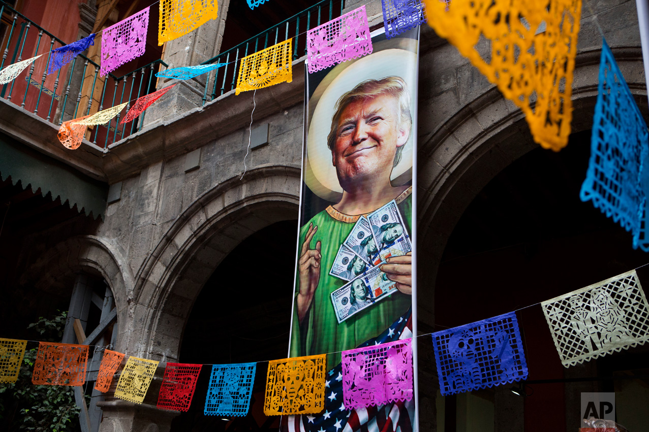  In this Nov. 10, 2016 photo, a banner with an image of Donald Trump promotes an exhibition titled; "Trump: A wall of caricatures," surrounded by intricately-cut tissue paper known as papel picado, inside the Caricature Museum in downtown Mexico City